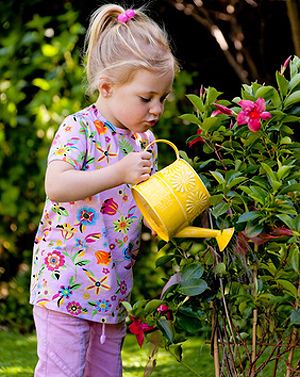 Mädchen gießt Blumen im Garten